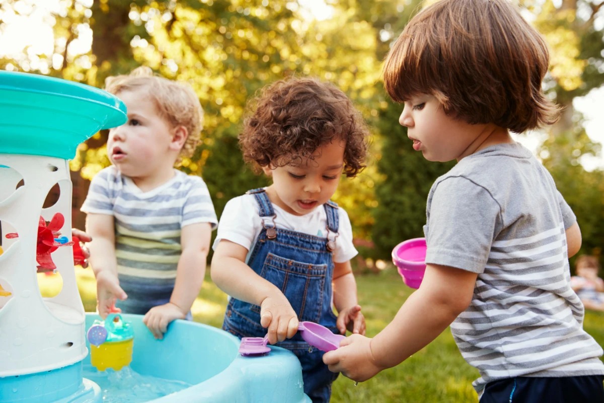 Toddlers exploring water play outdoors, learning through sensory experiences