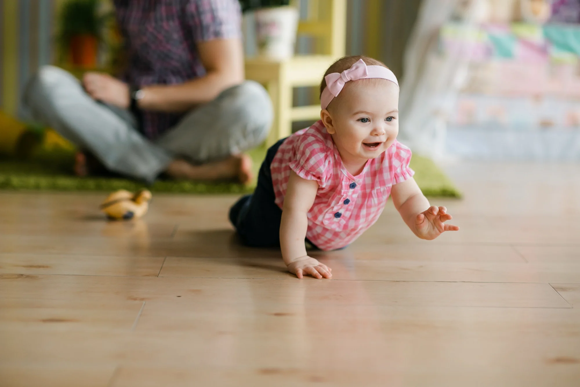 A baby exploring soft sensory toys on a colourful play mat in a tranquil early learning room environment.