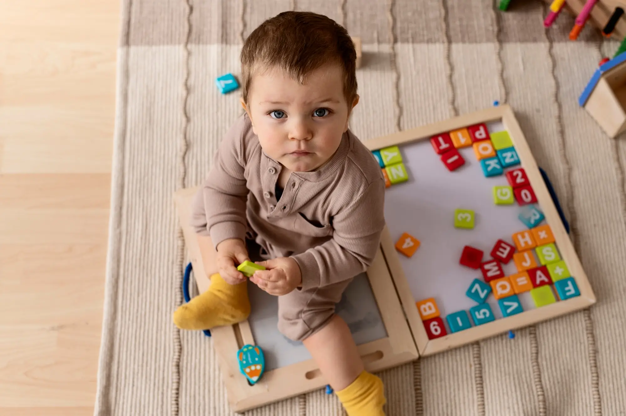 A toddler playing with educational letter blocks, focusing on early cognitive development in a well-equipped learning space.