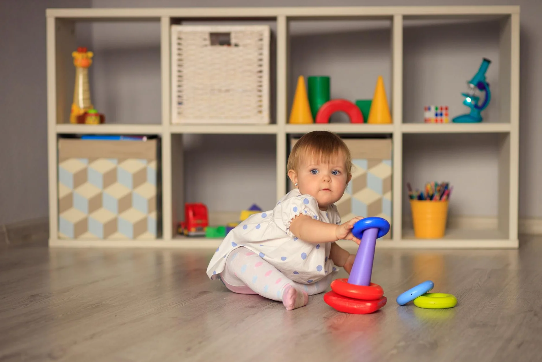 A young child sitting on the floor in a peaceful space, engaging with a plush toy in a safe, calm room.