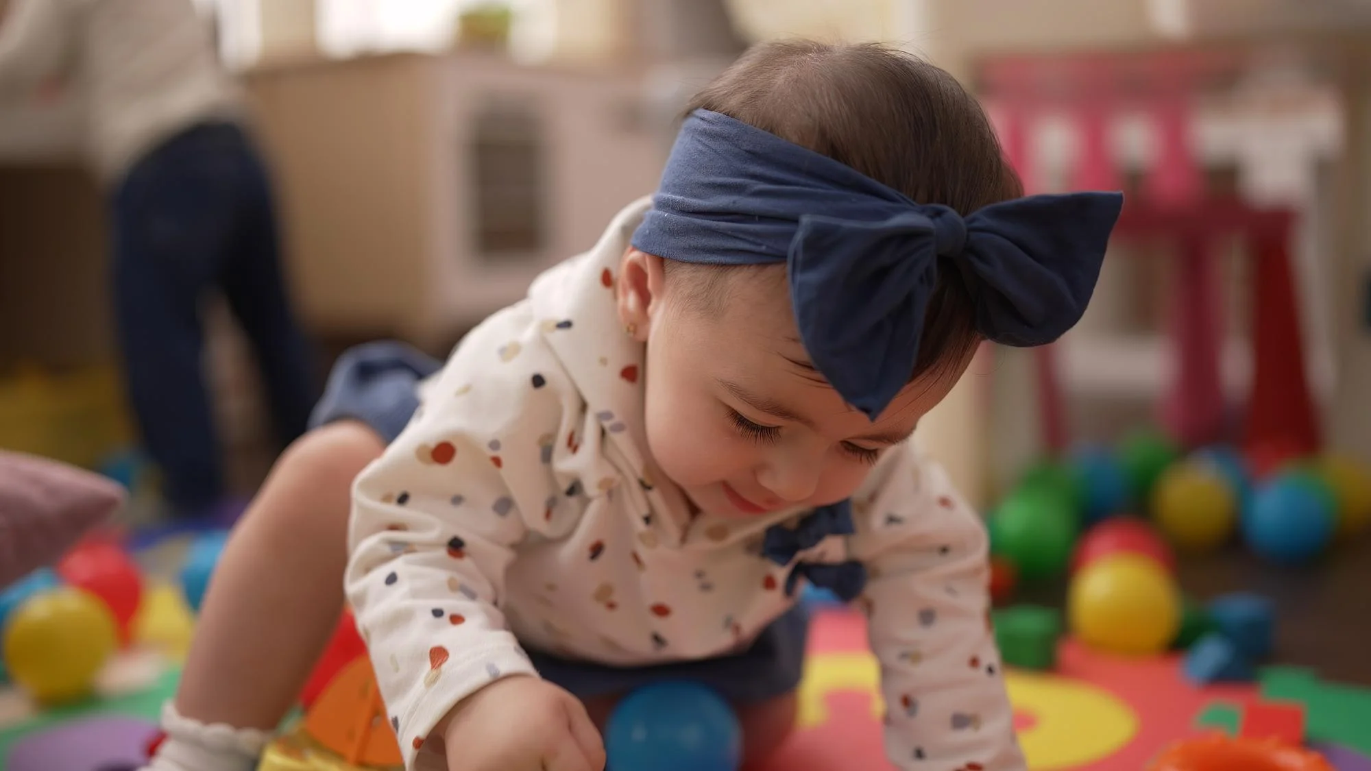 A baby enjoying time on a soft mat, surrounded by toys, in a nurturing environment tailored for early childhood growth.