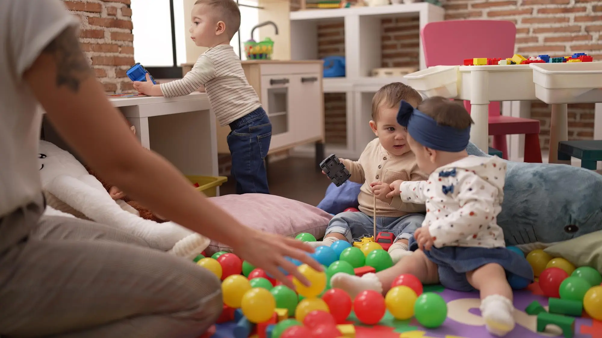 Toddlers engaging with colourful balls and building blocks, exploring their environment with sensory play and developing curiosity.
