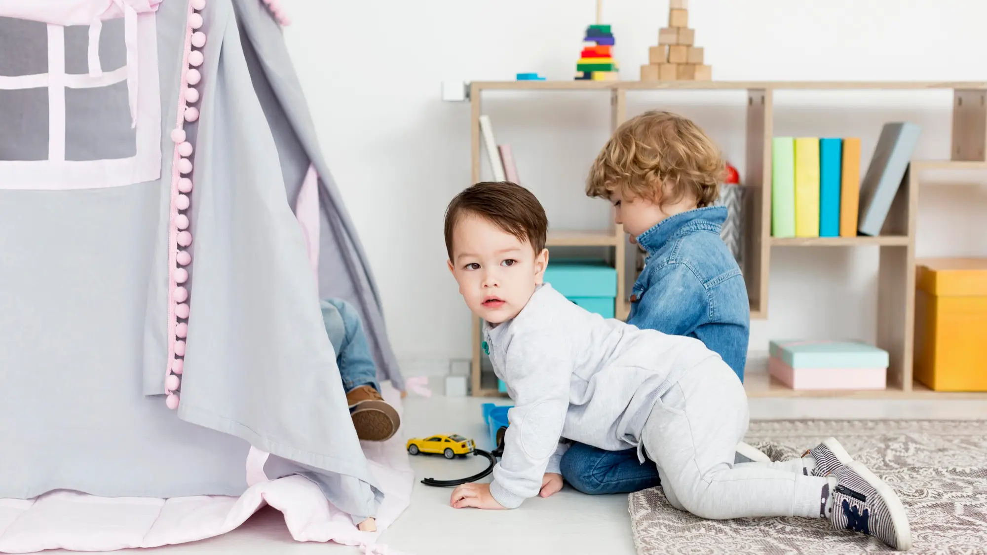 Two babies exploring a play area with colourful toys, encouraging social interaction and motor skill development