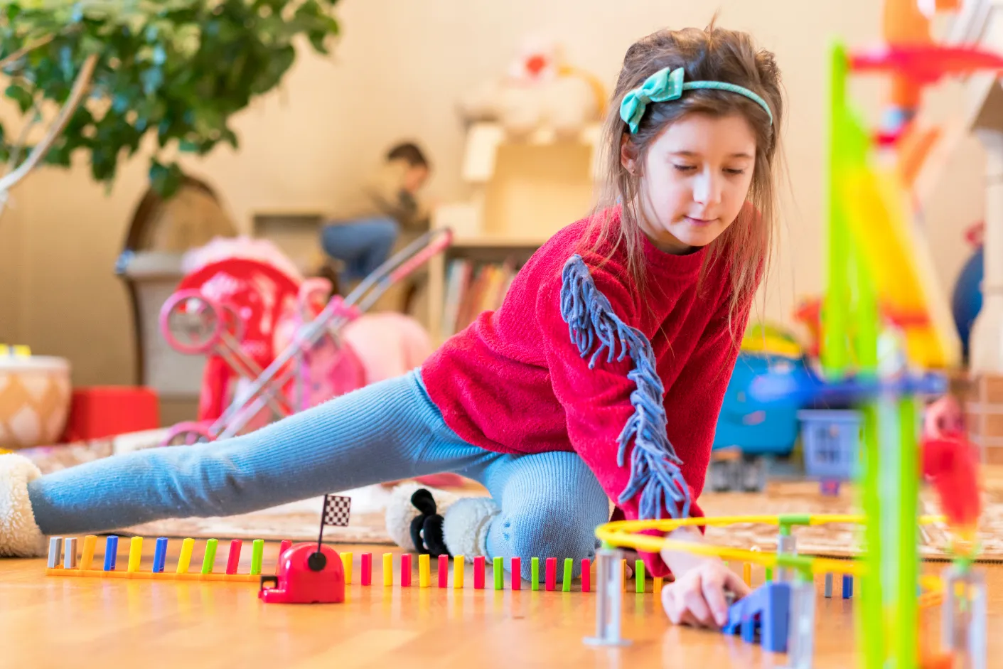 Child playing with a colourful domino setup and toy car track, enhancing coordination and problem-solving skills.