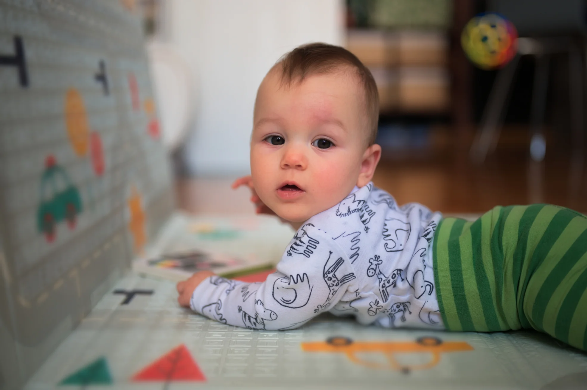A baby lying on a soft mat, reaching for toys in a safe and stimulating early learning environment.