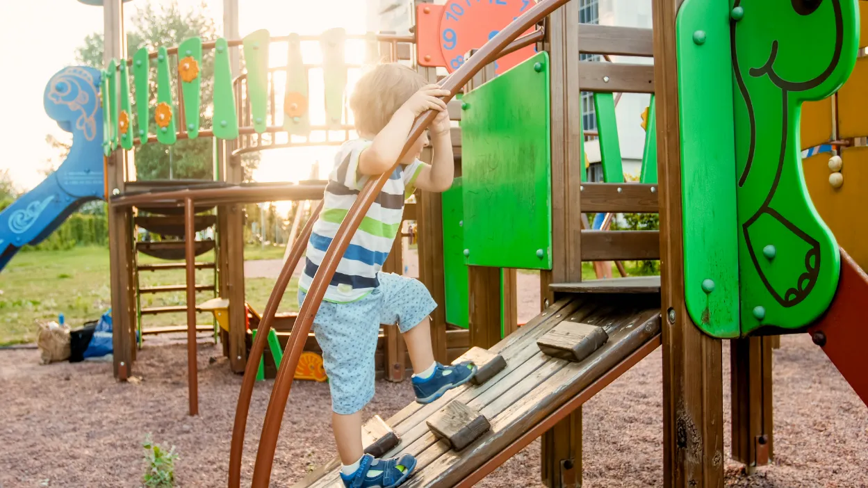 Child climbing a playground structure, developing physical strength and coordination.