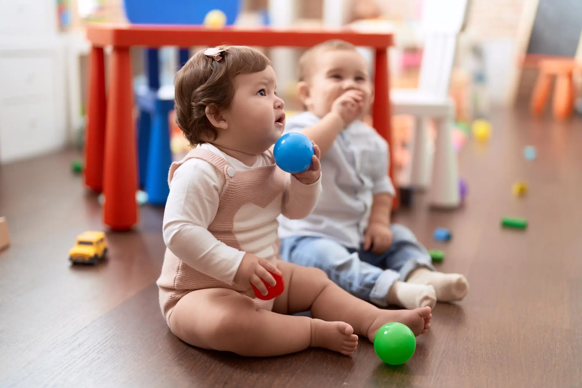 A baby plays with building blocks in a bright playroom, focusing on hand-eye coordination and early developmental play.