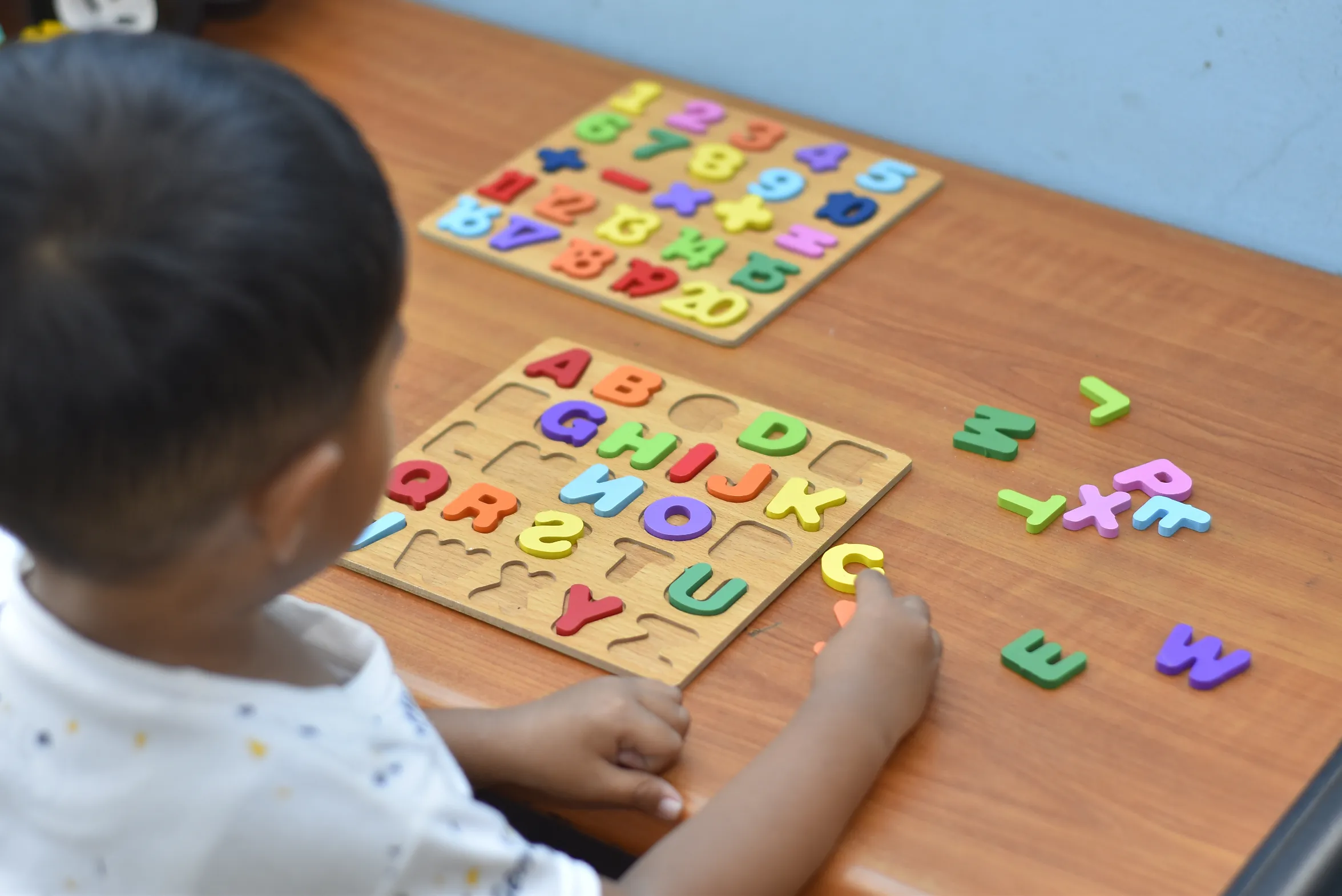 Child interacting with puzzle pieces, enhancing early literacy and cognitive development through play.