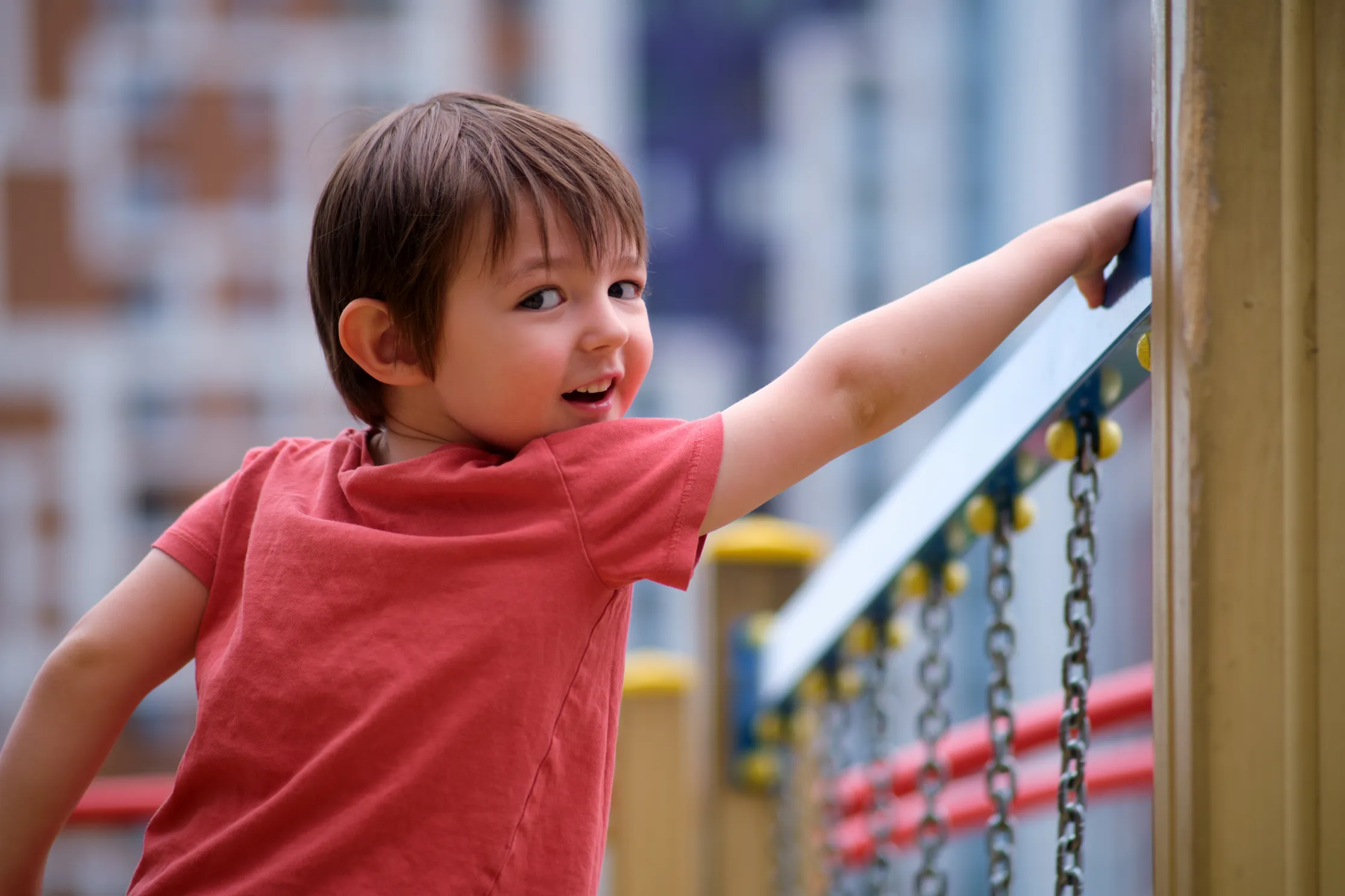 A young boy enjoys playing on a climbing structure at an outdoor playground, enhancing physical development and confidence through active play.
