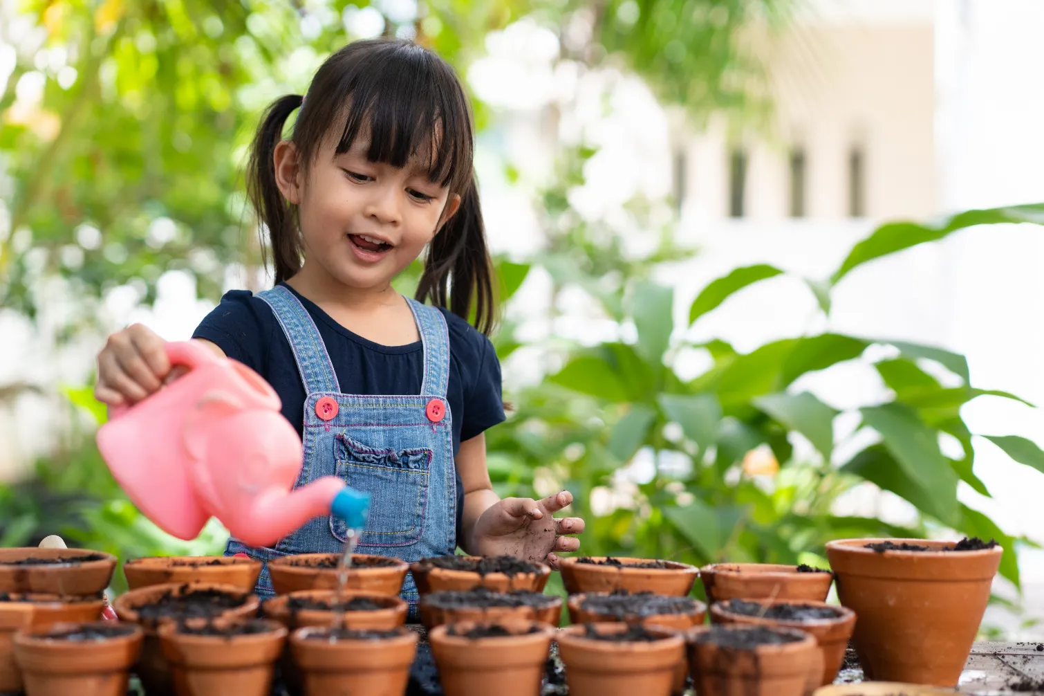 Child pouring water into a toy cup as part of sensory play, encouraging fine motor skills and hands-on learning.