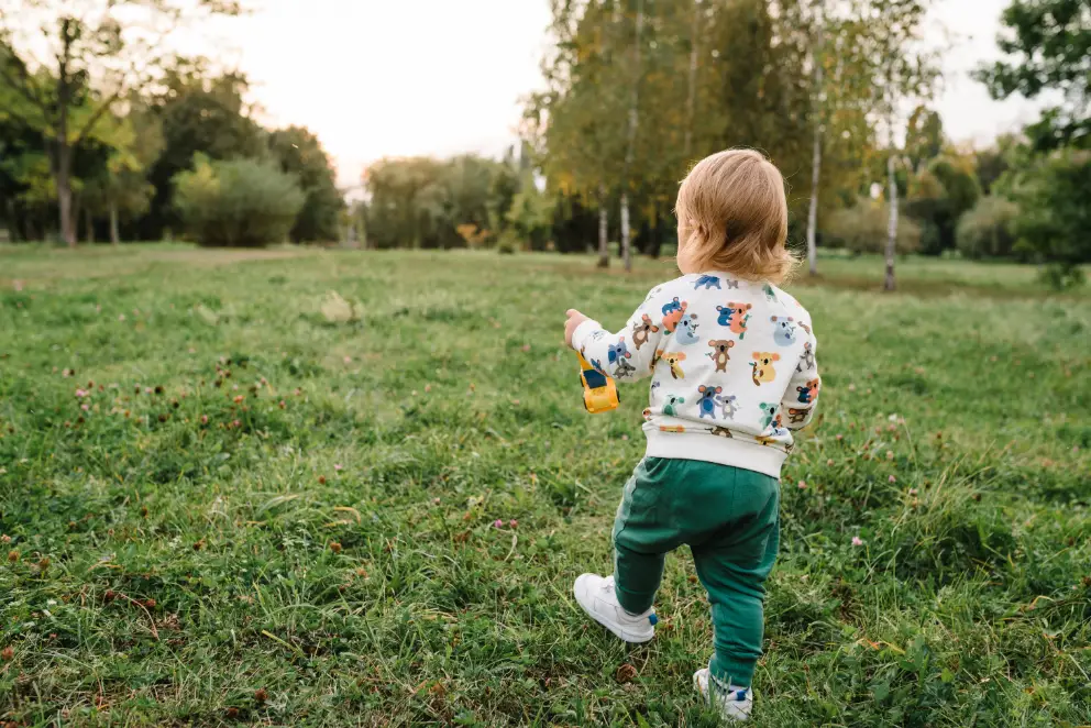 Toddler exploring grassy outdoor space for active play