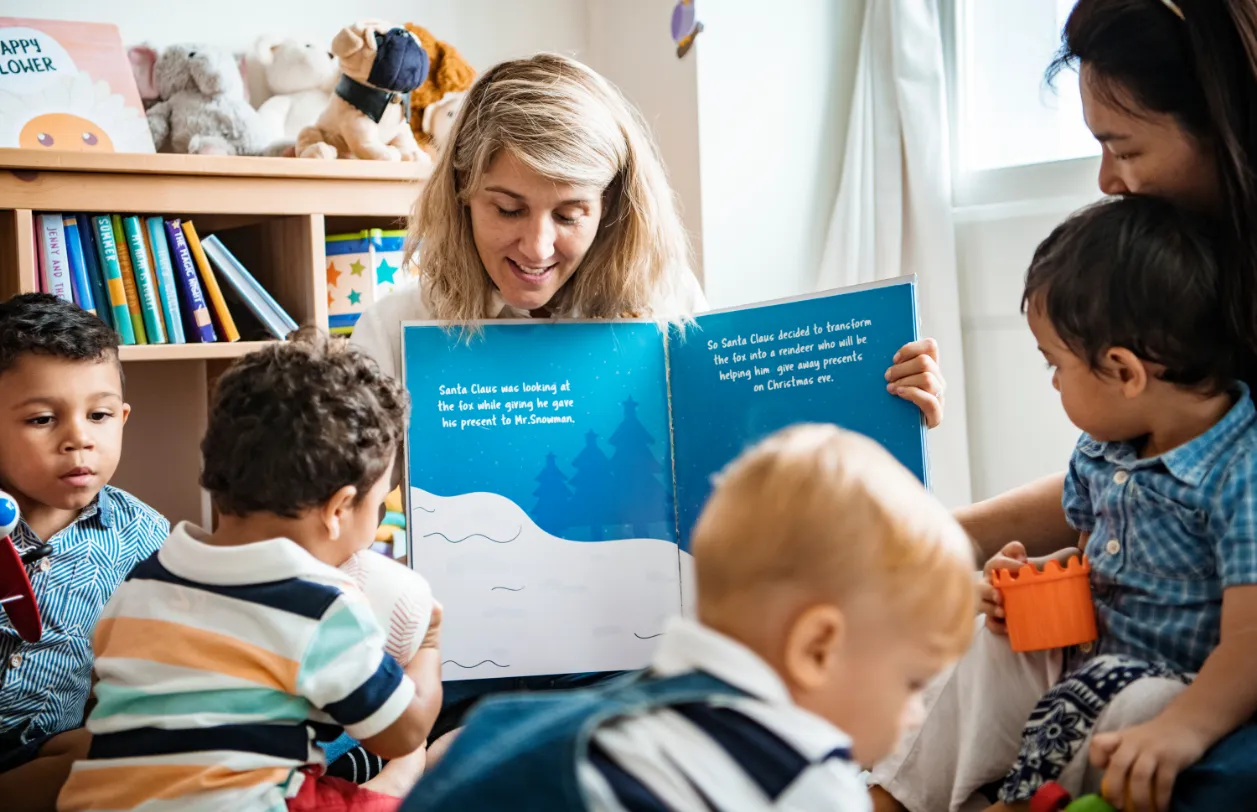 Educators reading with toddlers, supporting early language development and discovery in the Giraffe Room