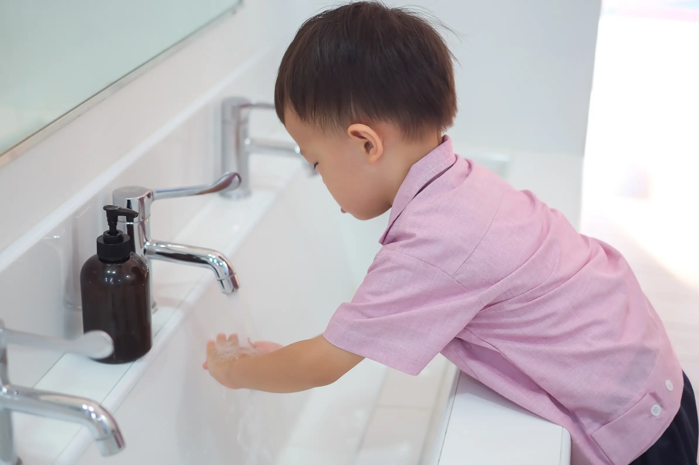 Toddler washing hands at low sink to encourage independence