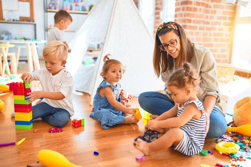 Toddlers building with blocks and playing together with support from an educator in the Zebra Room